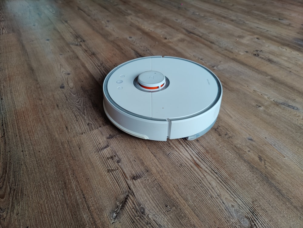 a white robot vacuum on a wooden floor