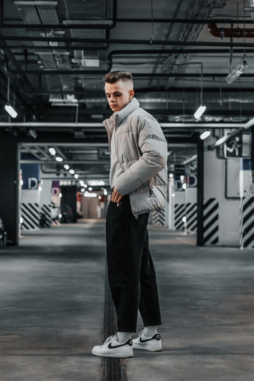 a man standing in a parking garage with his hands in his pockets