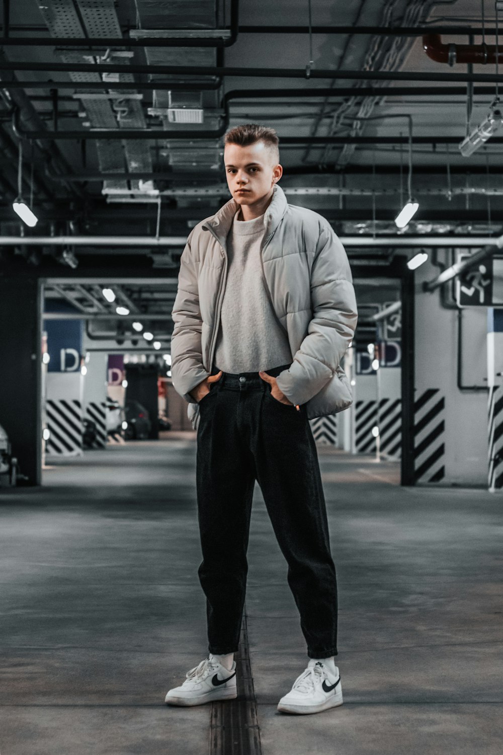 a man standing in a parking garage with his hands in his pockets