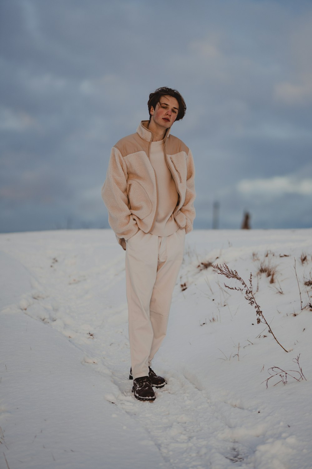 a man standing in the snow with his hands in his pockets