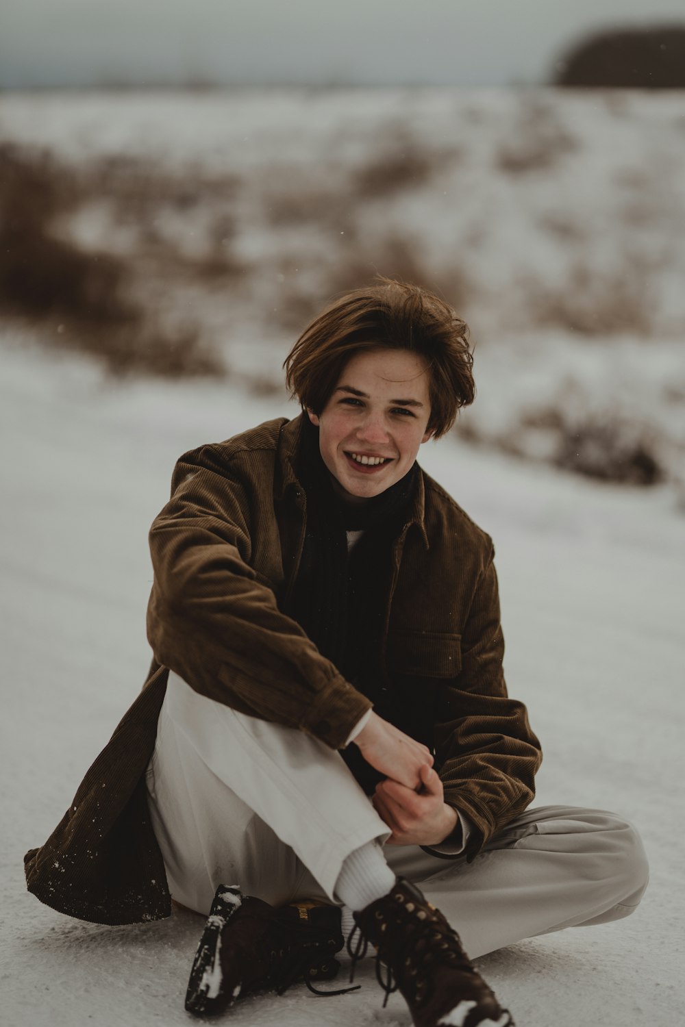 a young man sitting in the snow smiling