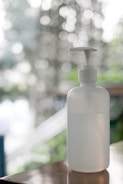Close-up of eco-friendly disinfectant spray bottle with green leaves background.
