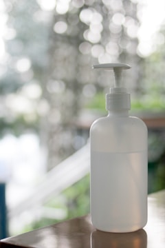 Close-up of eco-friendly disinfectant spray bottle with green leaves background.