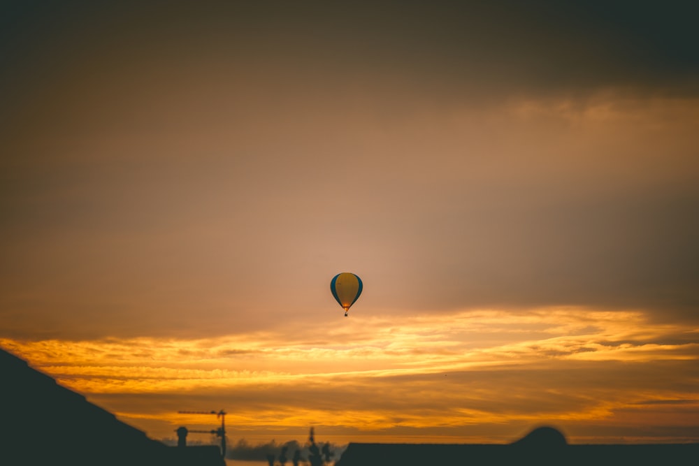 a hot air balloon flying in the sky at sunset