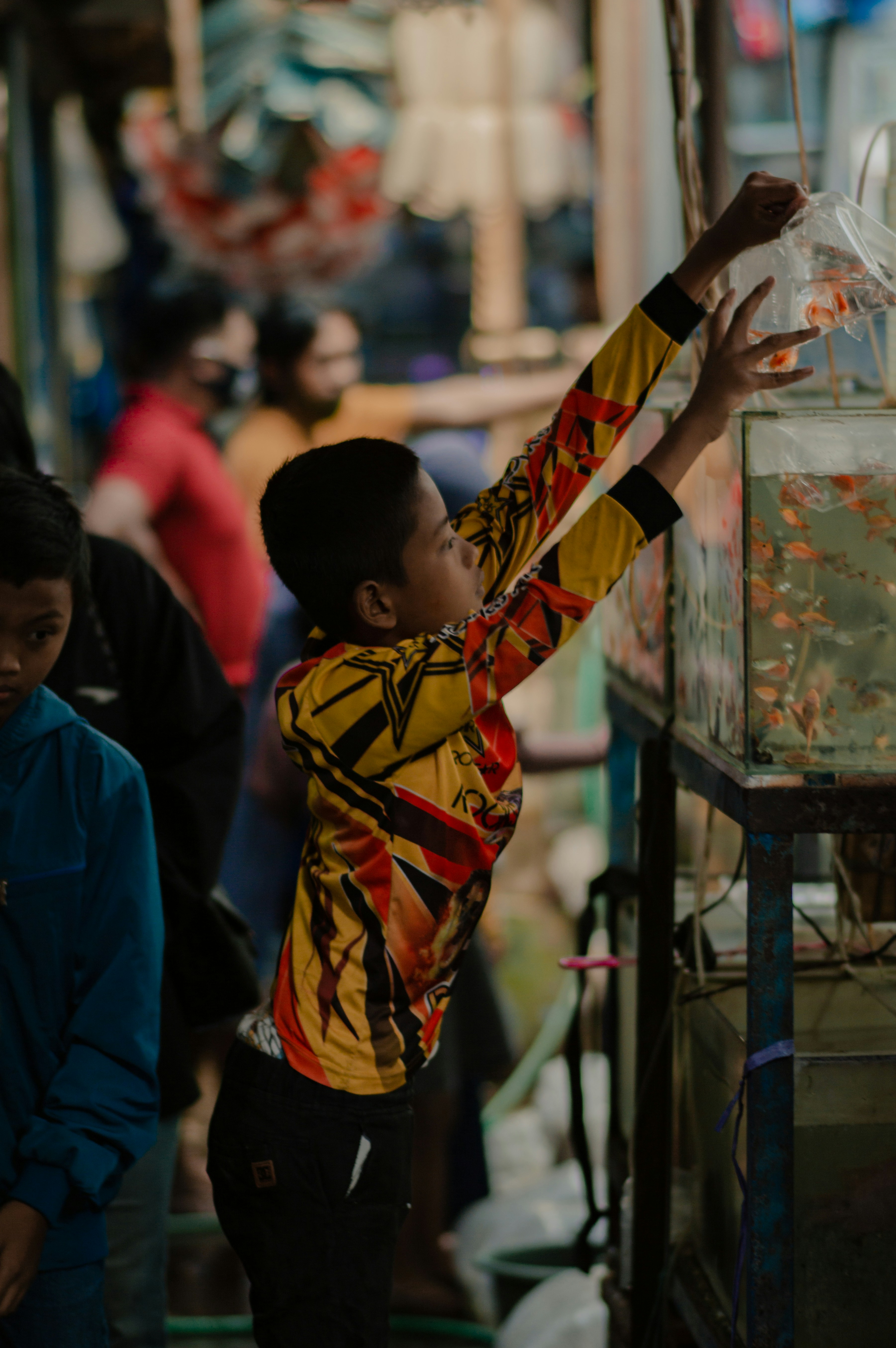 Seorang anak laki-laki meraih ikan di dalam tangki