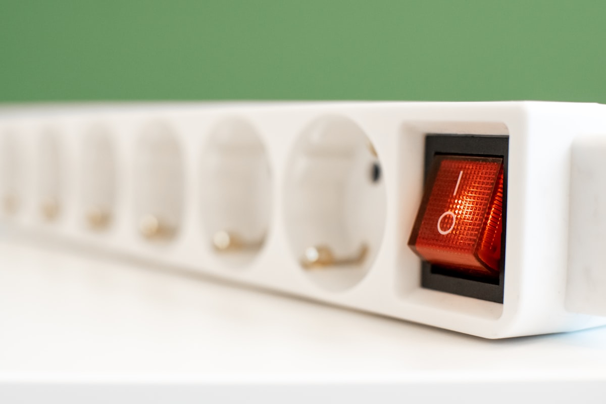 Zapatilla eléctrica blanca de varios enchufes con el interruptor rojo iluminado encendido