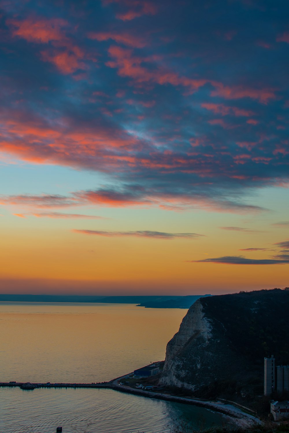 a sunset over a body of water with a lighthouse in the distance