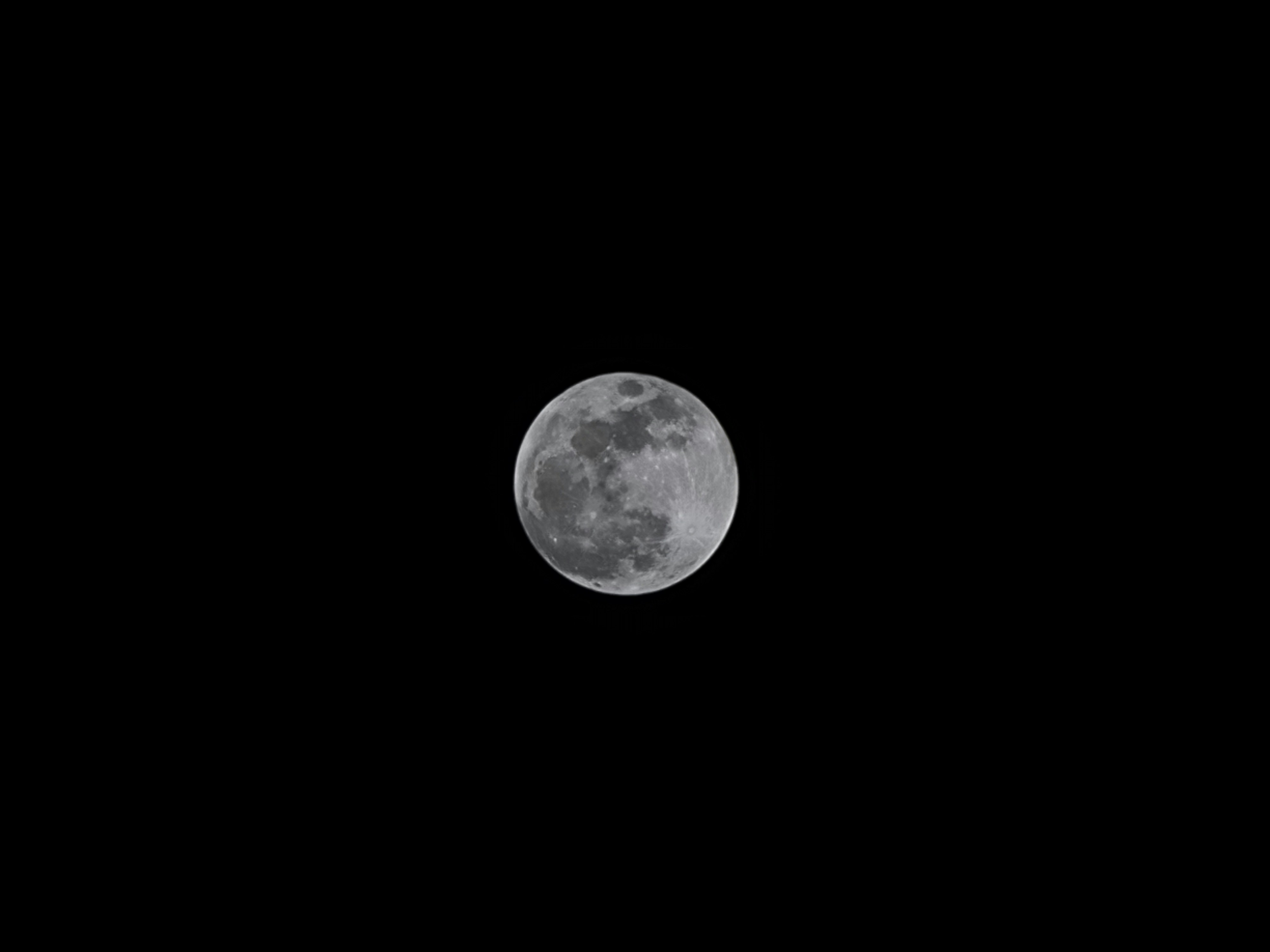 a full moon is seen in the dark sky