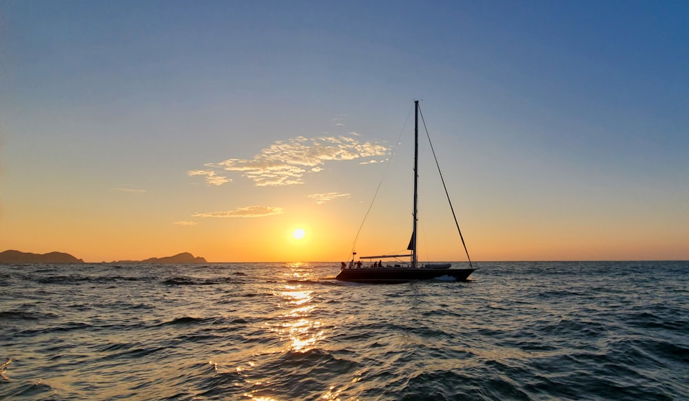 a sailboat in the ocean at sunset