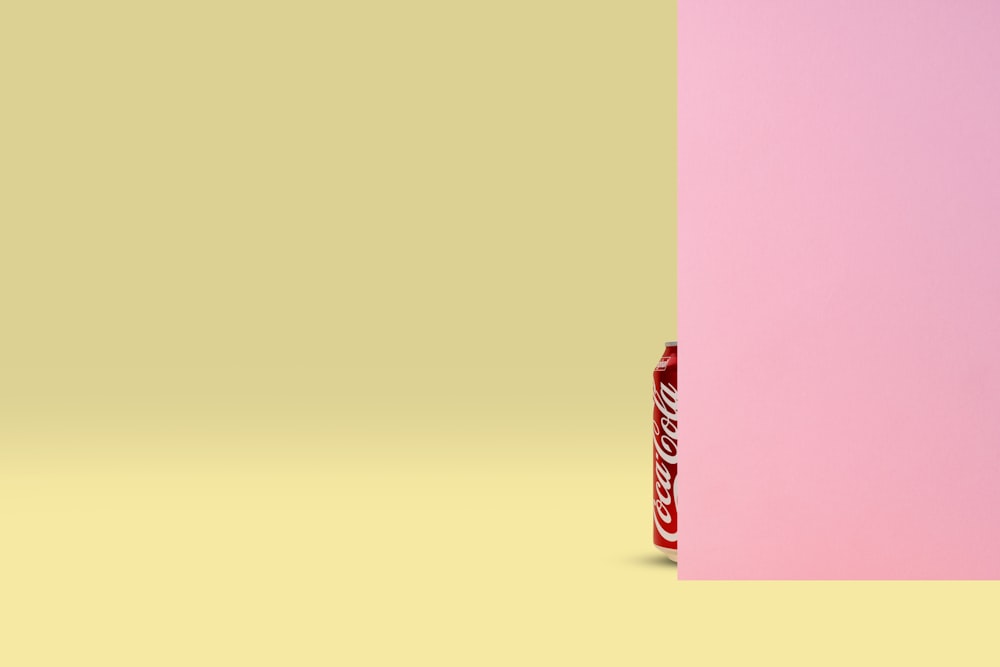 a can of soda on a pink and yellow background