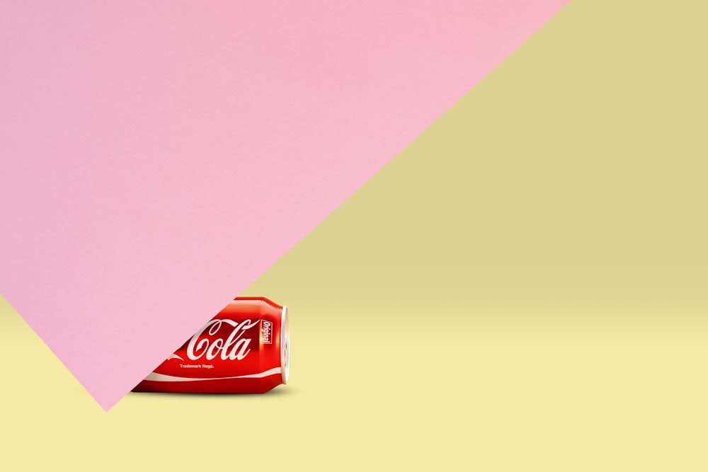 a pink and yellow background with a coca - cola bag