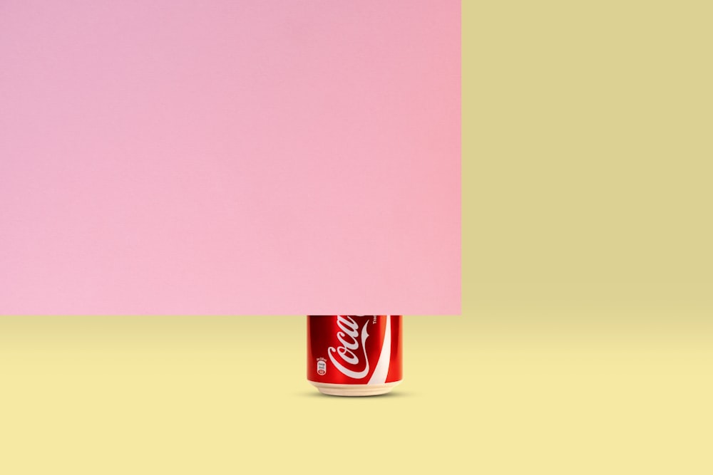 黄色とピンクの背景にコカの缶 – コーラ