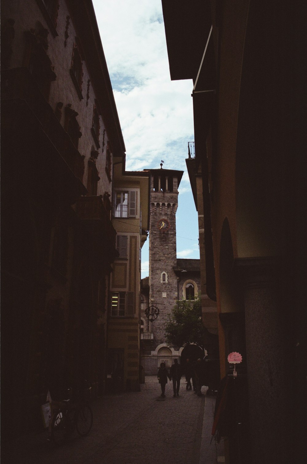 people walking down a narrow street in a city
