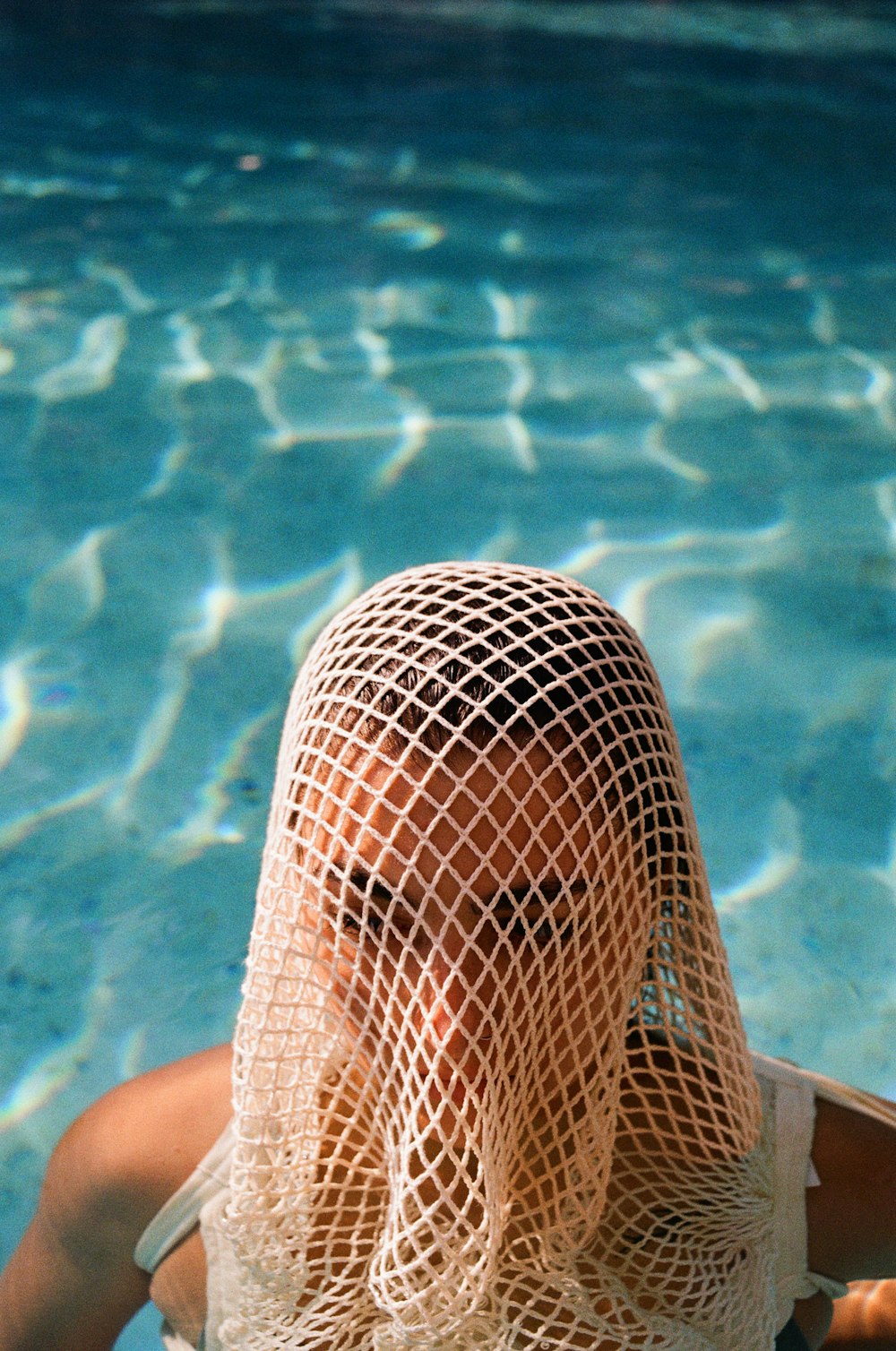 a woman wearing a netted hat in a swimming pool