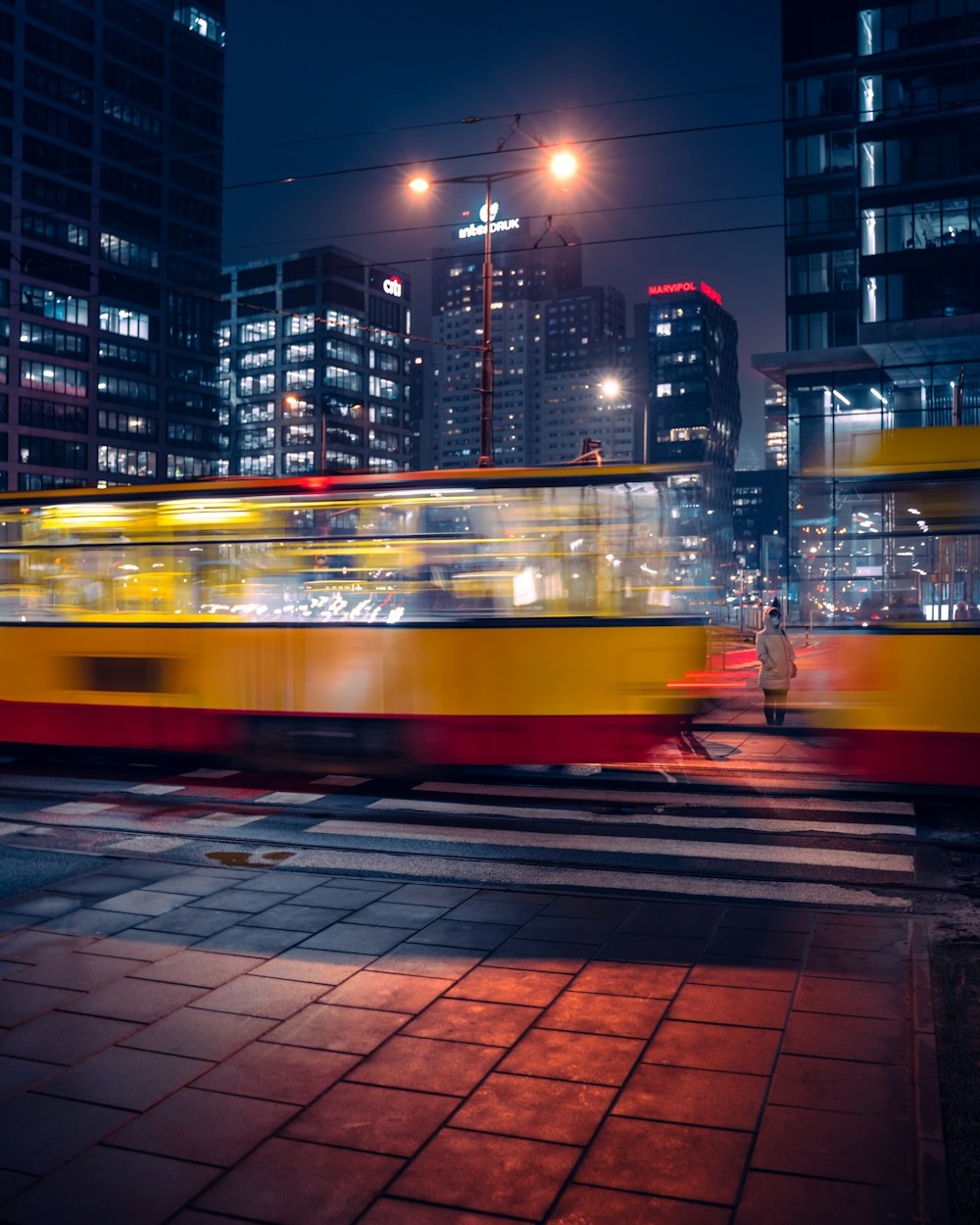 a yellow and red train traveling through a city at night