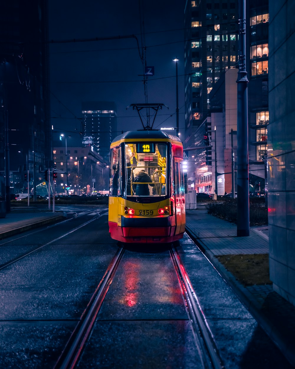 a red and yellow trolley on a city street at night
