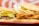 Two sandwiches are placed side by side on a red tray. One sandwich contains a beef patty with lettuce and cheese, while the other features fried chicken with bacon and lettuce. The bread appears soft and slightly toasted. The background features a blurred red and white pattern.