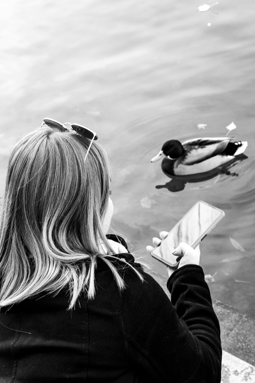 a woman is looking at her cell phone near a duck