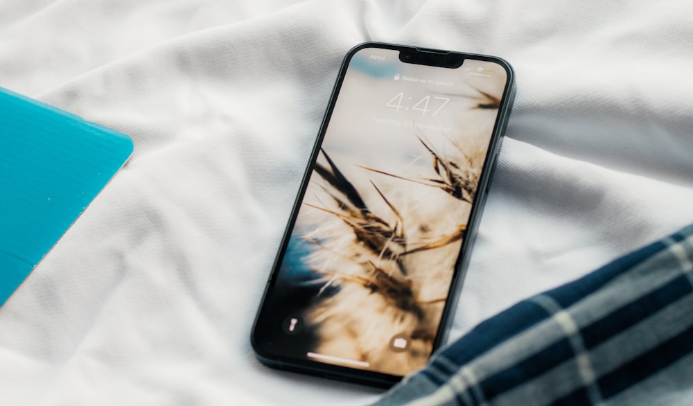 a cell phone sitting on top of a bed next to a laptop