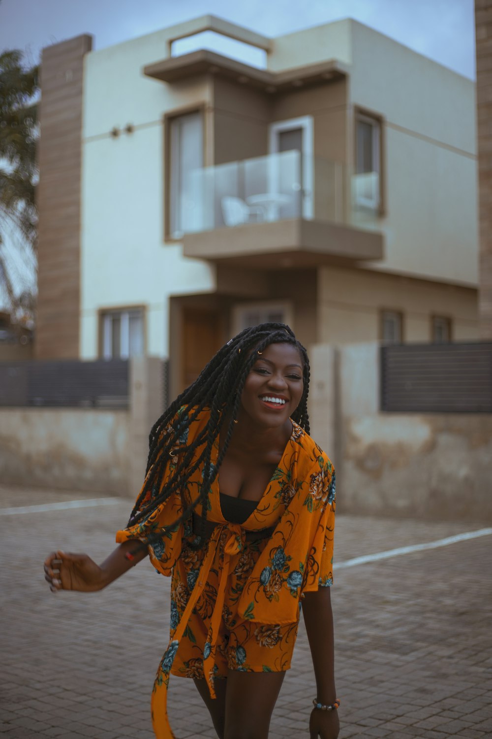 a woman with dreadlocks walking in front of a house