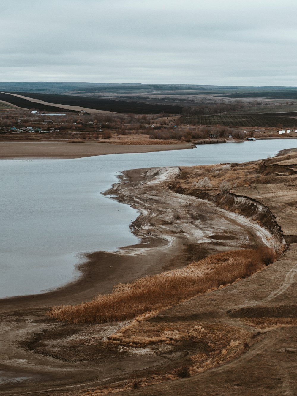 a large body of water surrounded by dry grass