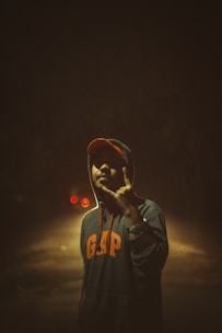 Close-up of a sleek black hoodie with neon orange custom embroidery glowing under urban lights.