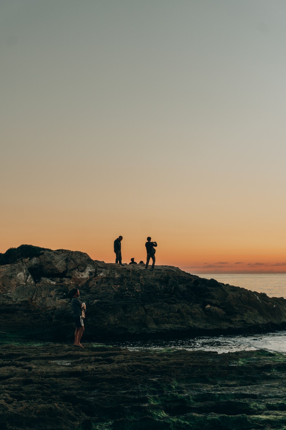 a couple of people standing on top of a rocky beach