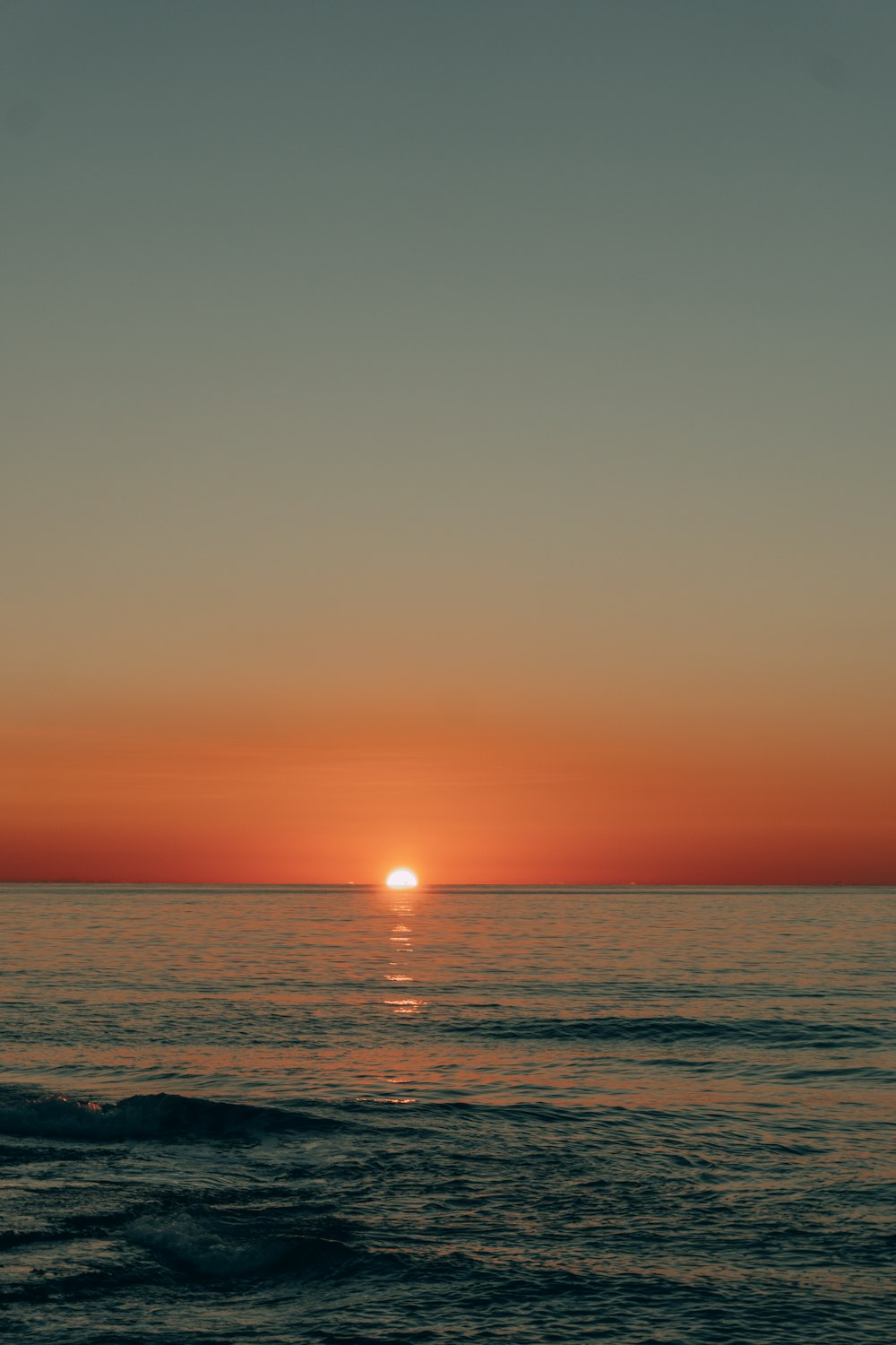 the sun is setting over the ocean on a clear day