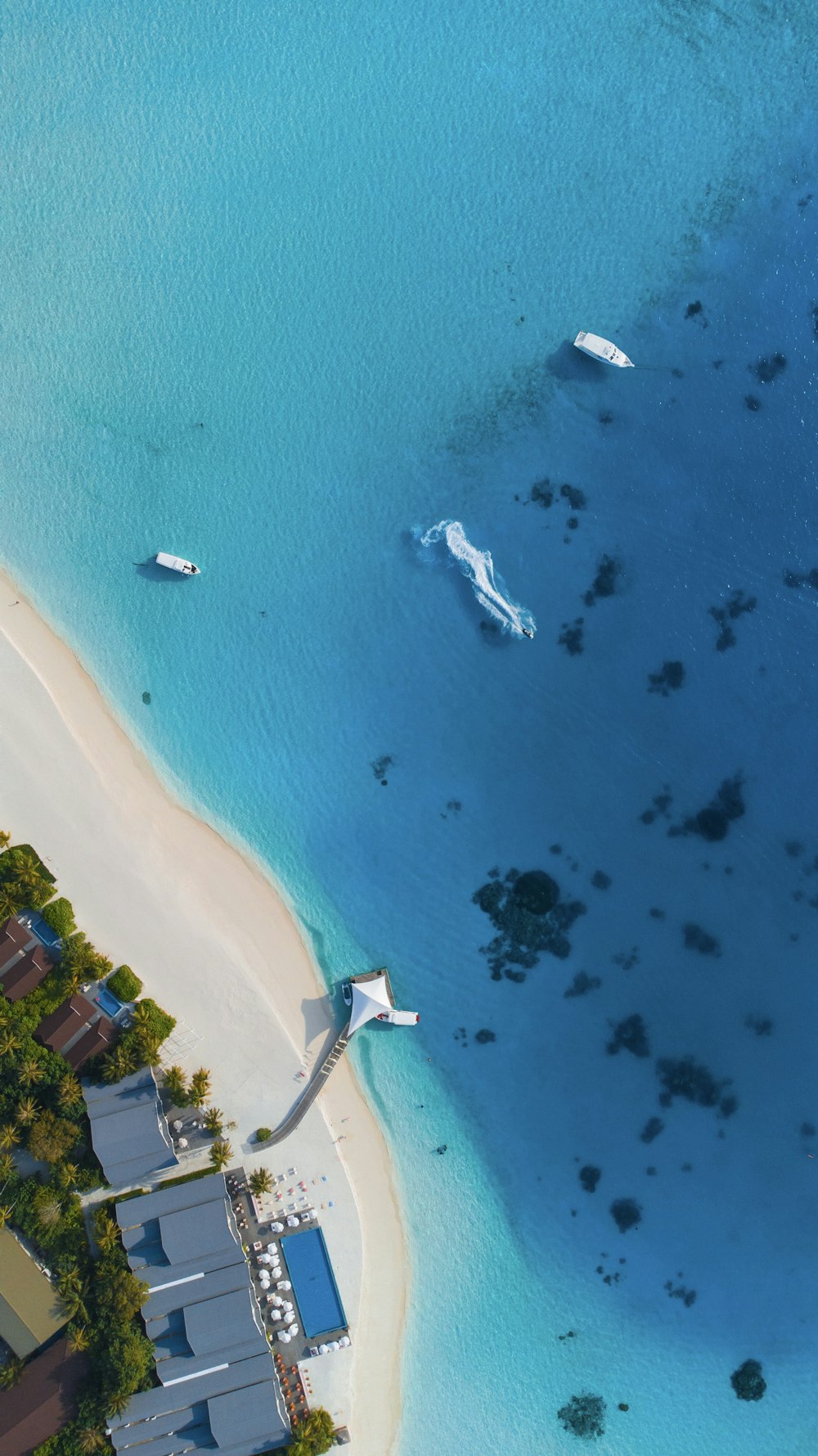 an aerial view of a beach with boats in the water