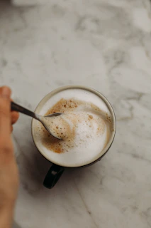 A compact handheld milk frother in action, creating creamy foam atop a cup of coffee.