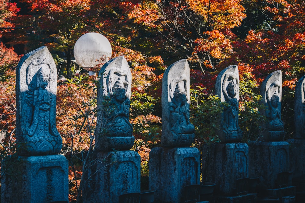 a row of stone heads in front of a forest