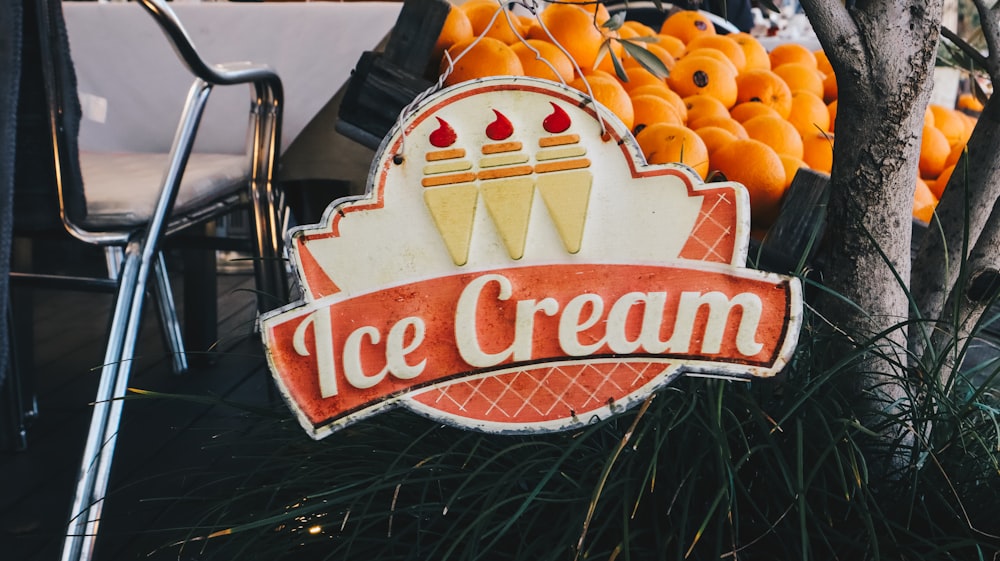 an ice cream sign sitting next to a pile of oranges