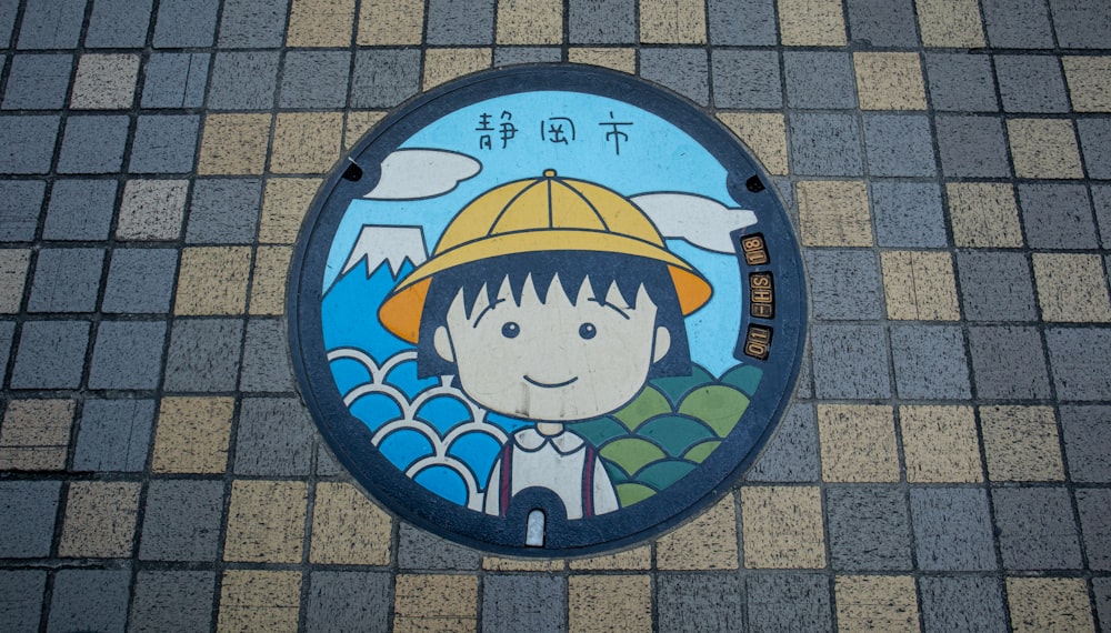 a manhole cover with a picture of a boy wearing a yellow hat