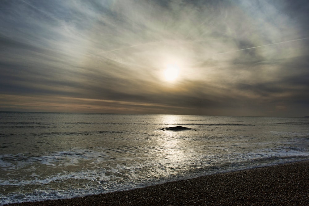 the sun is shining through the clouds over the ocean