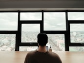 A confident professional reviewing financial reports in a cozy office with New England cityscape visible through the window.