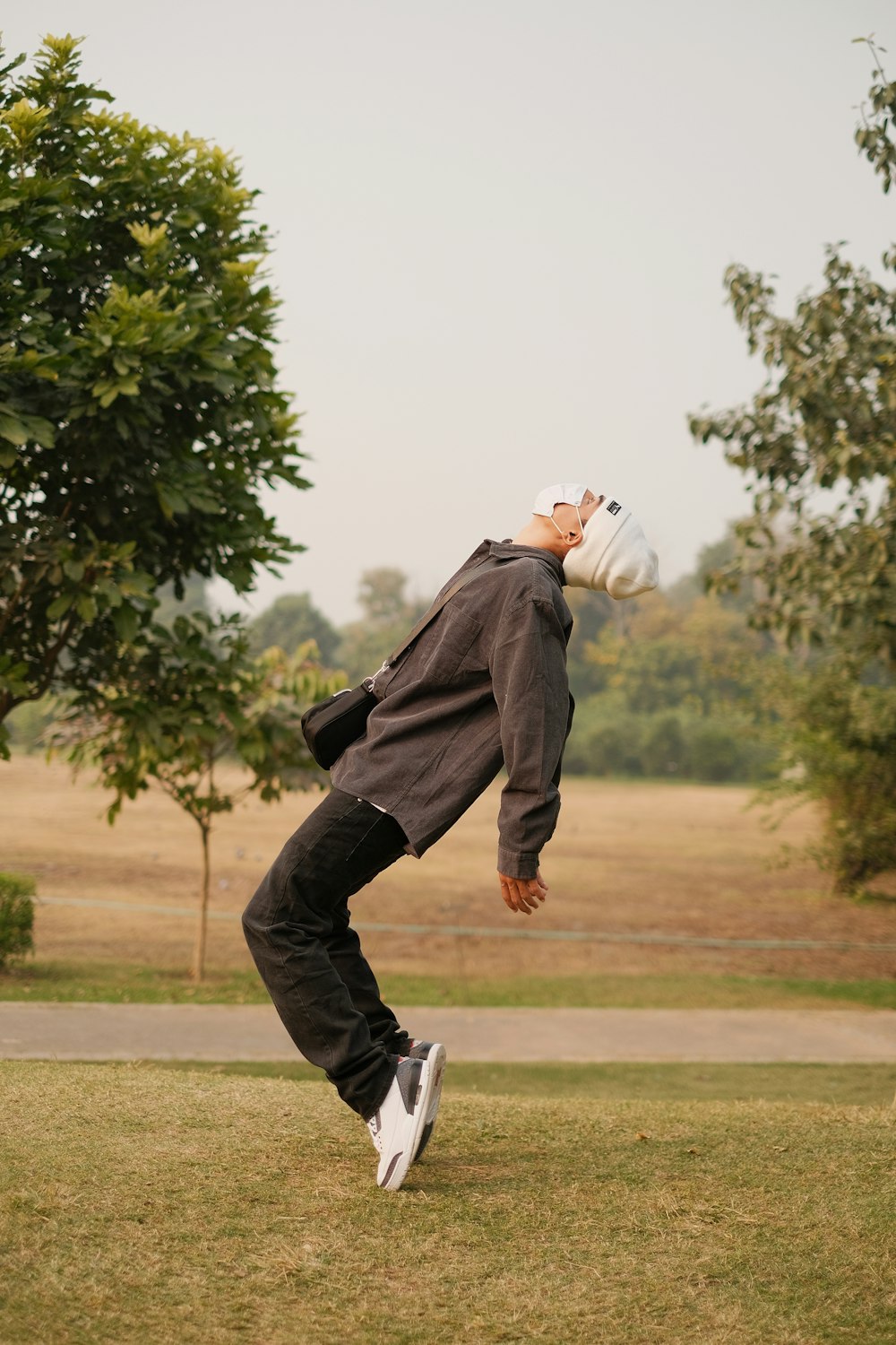 a man standing in the grass with a frisbee in his mouth