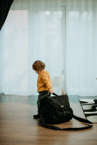 a young boy sitting on the floor with a black bag