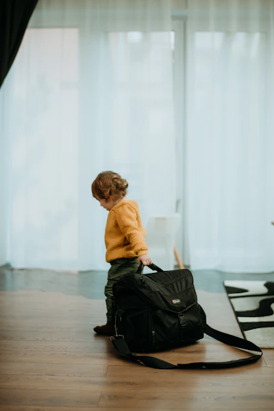 a young boy sitting on the floor with a black bag