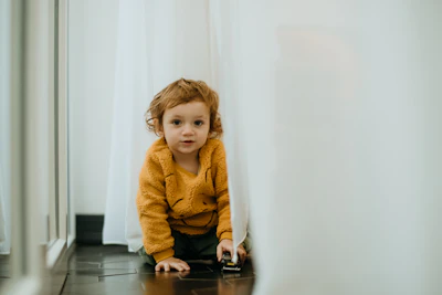a young child sitting on the floor in front of a mirror