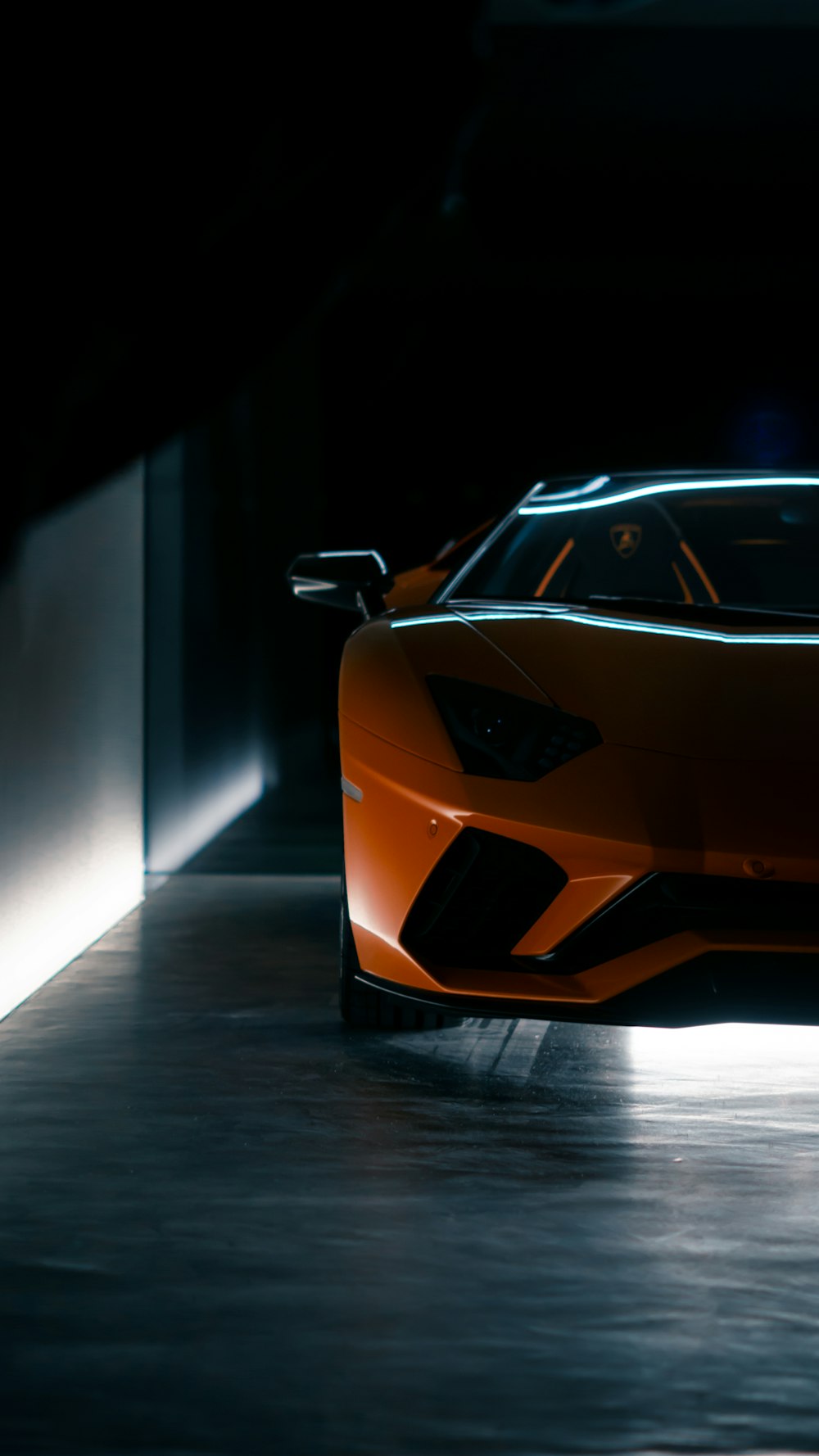 an orange sports car in a dimly lit room