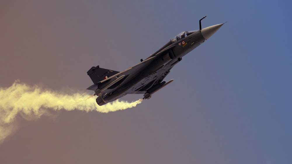 a fighter jet flying through a cloudy blue sky