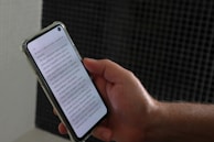 a person holding a smart phone with a book on the screen