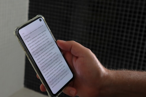 a person holding a smart phone with a book on the screen