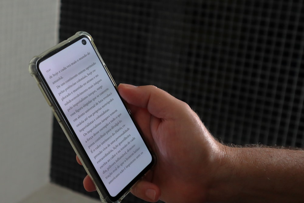 una persona che tiene uno smartphone con un libro sullo schermo