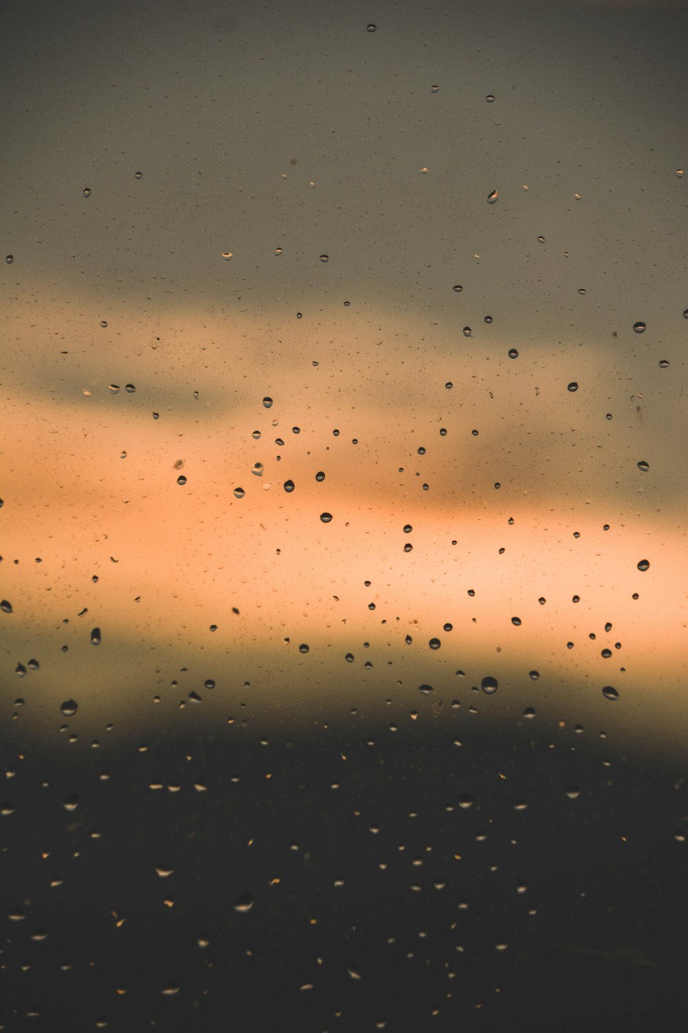 rain drops on a window with a sunset in the background
