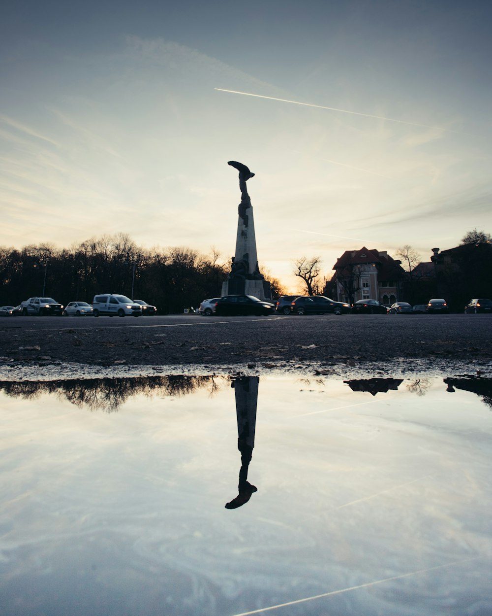 a reflection of a statue in a puddle of water