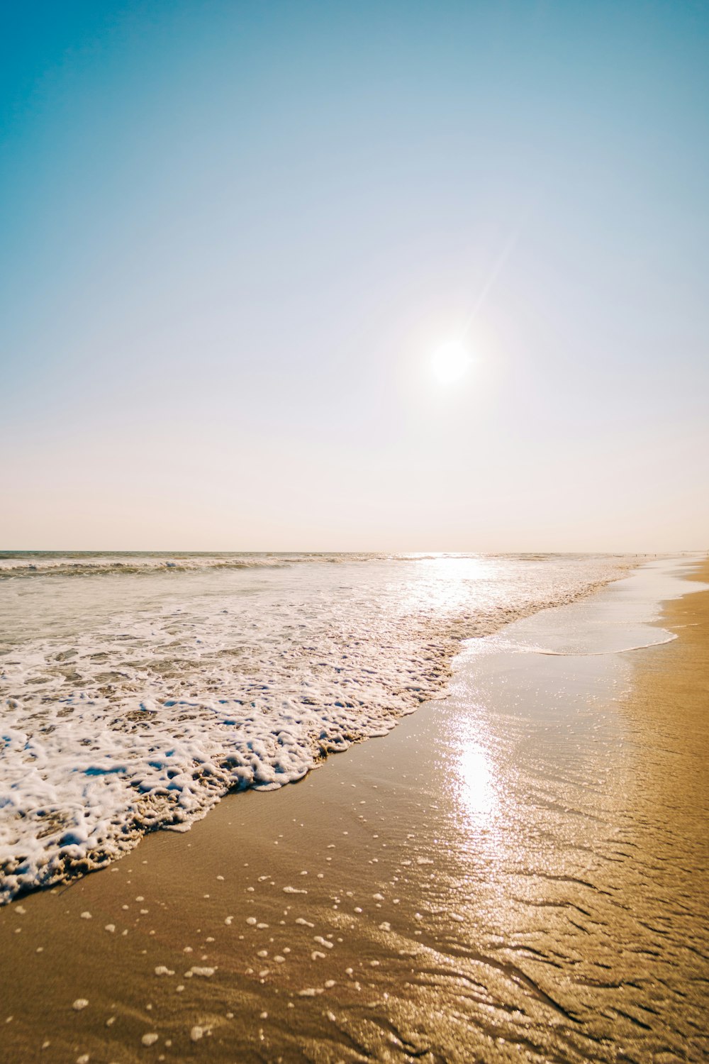 the sun is shining over the water at the beach