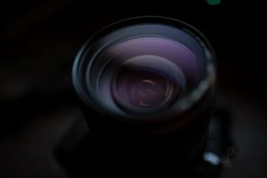 Close-up of a high-end camera lens reflecting studio lights in a dark, moody environment.
