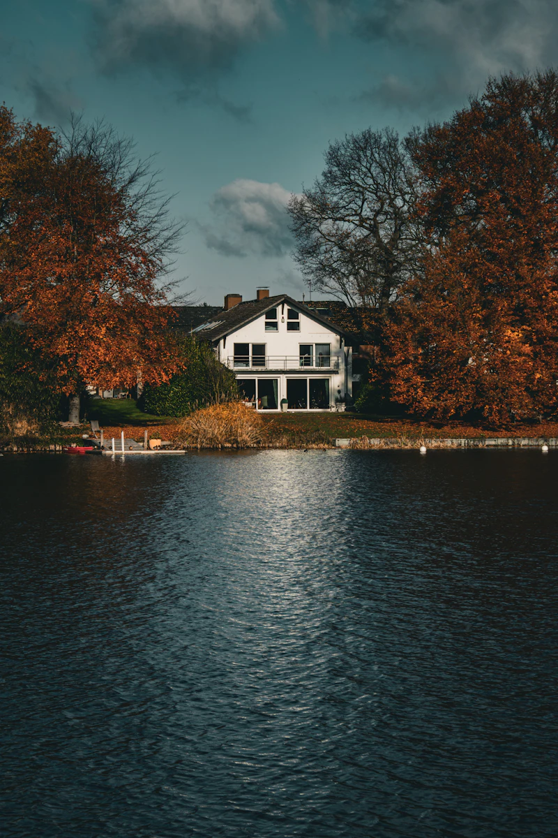 Lakefront house with autumn foliage and calm water reflection