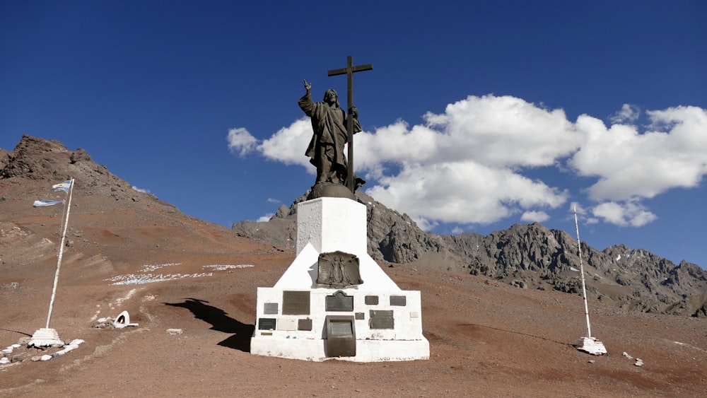 a statue of a man holding a cross on top of a hill